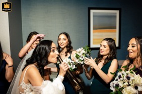 The bride takes a celebratory drink as her bridesmaids laugh and cheer before the wedding at Hilton Philadelphia at Penn’s Landing in Philadelphia, Pennsylvania